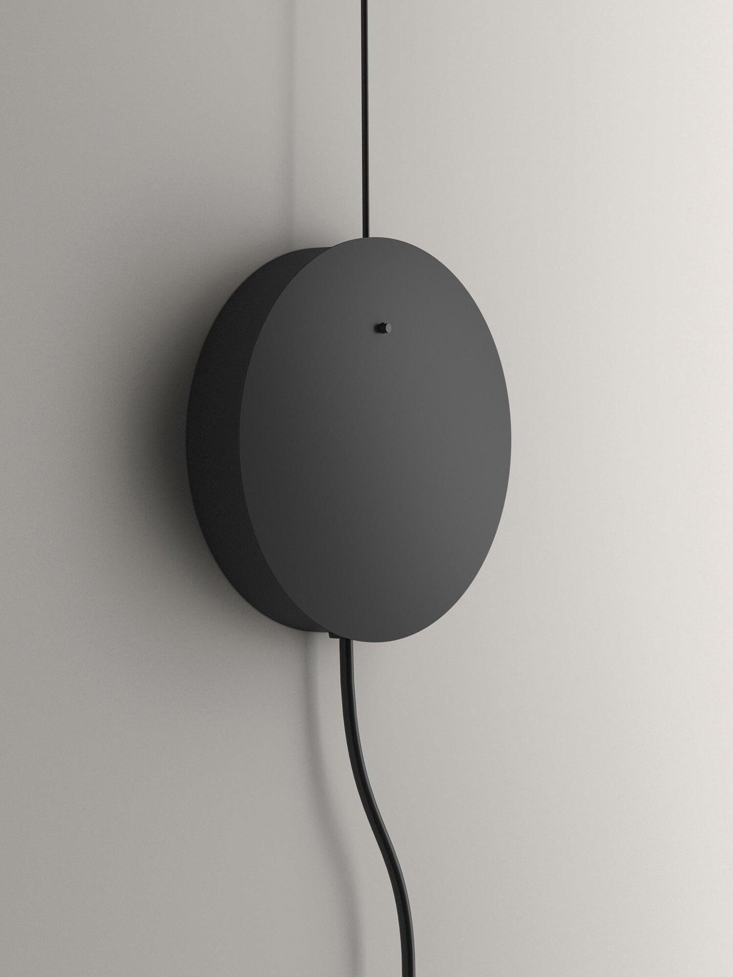 Close-up of a round black wall plate with upper cable and two lower leads