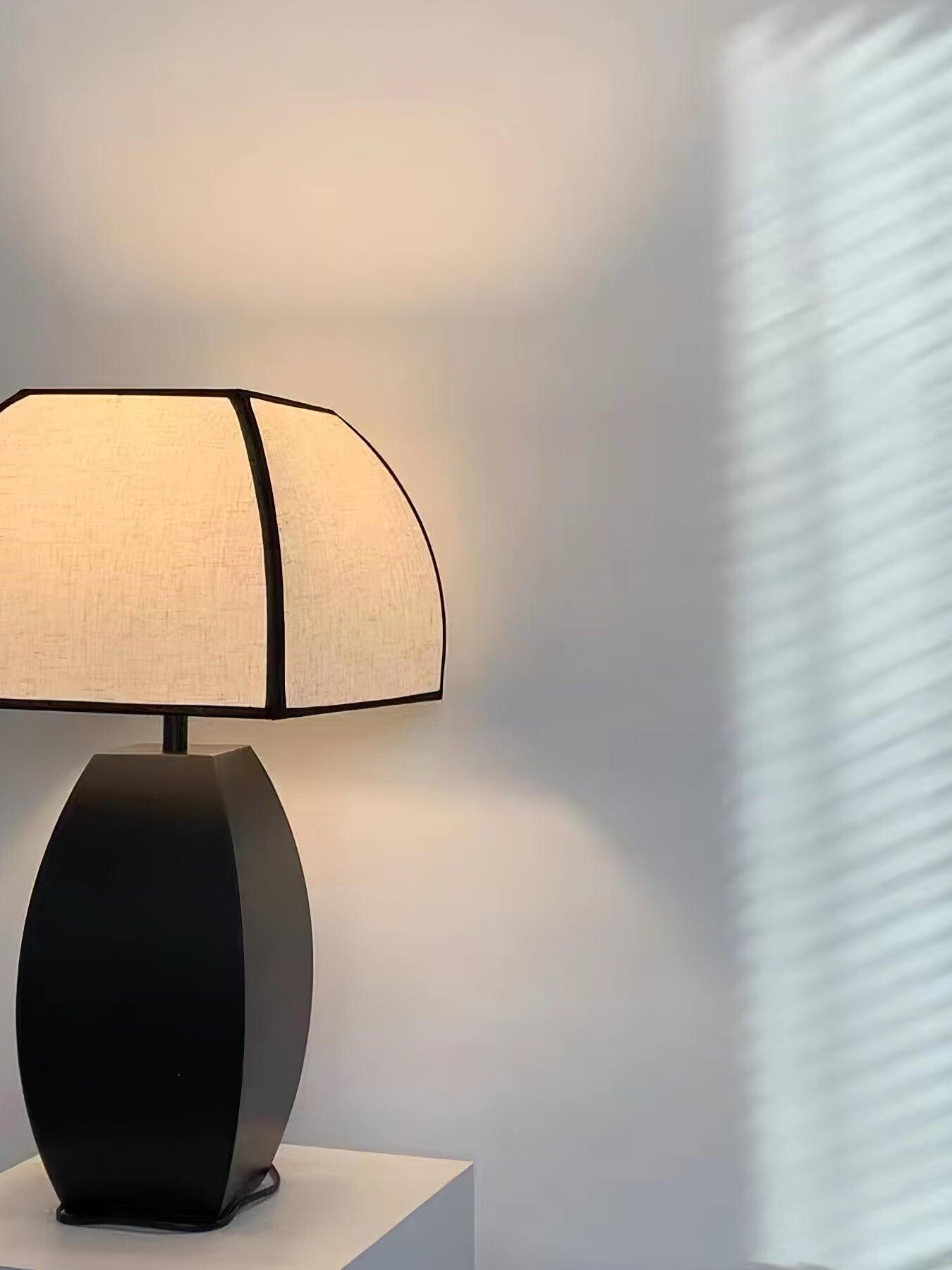 Black-base Javier lamp lit against pale wall