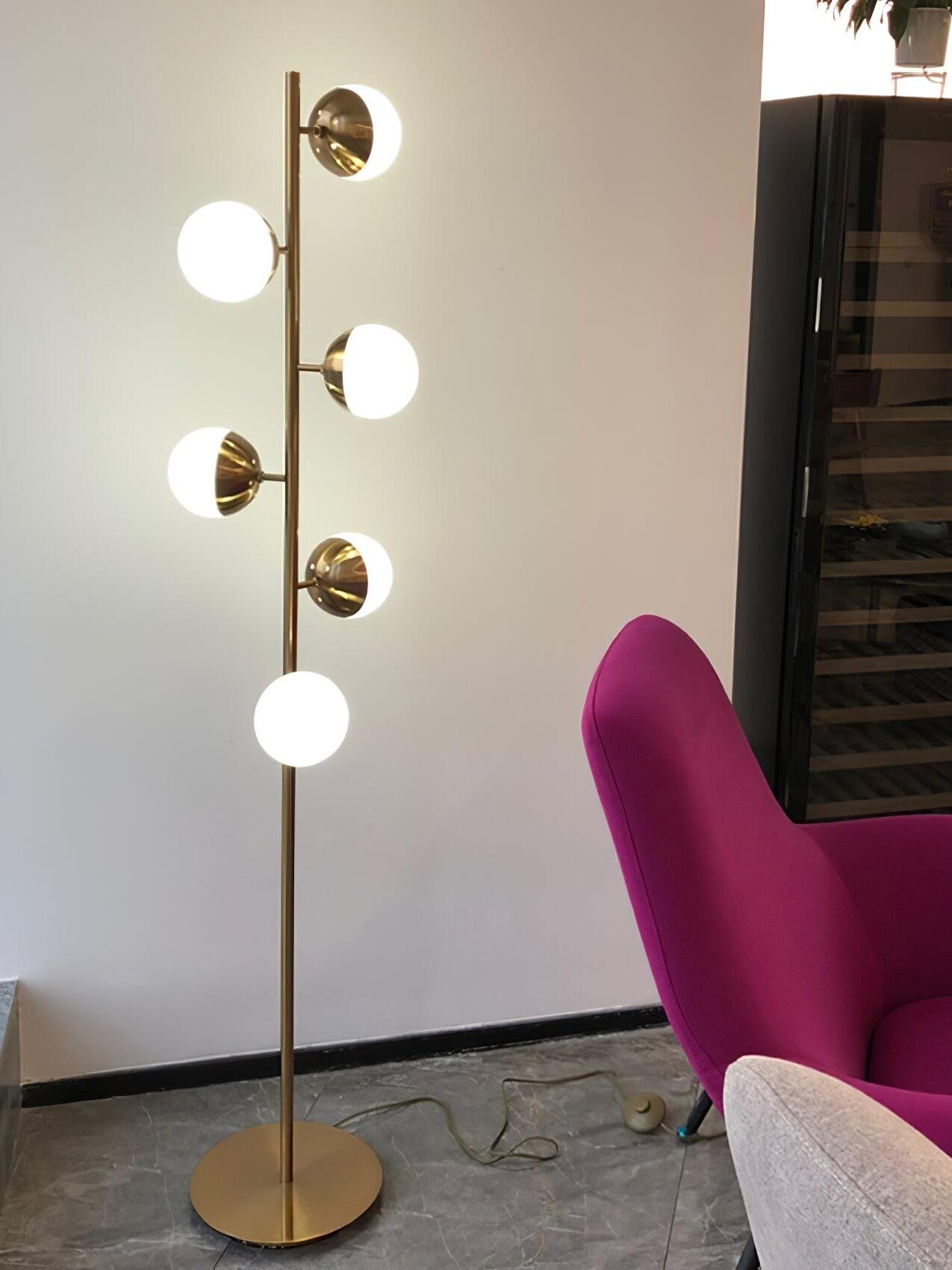 Tall gold globe lamp beside magenta chair