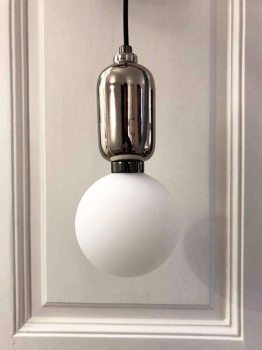 Reflective metal cap above a white glass globe