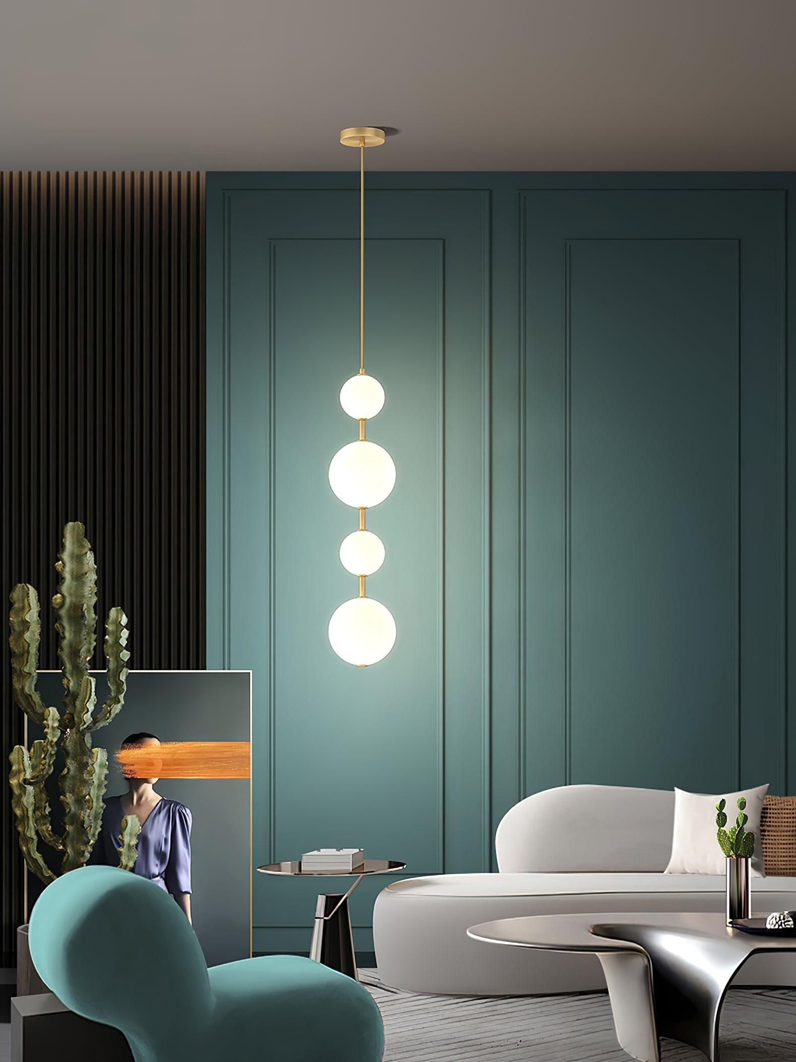 Four-globe pendant lit before teal wall panels above living-room seating and a side table