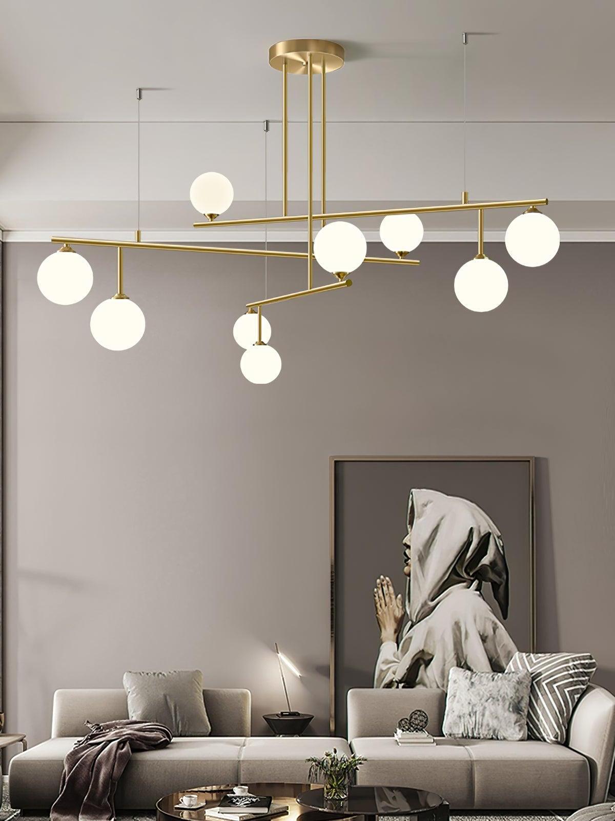 Arteriors globe chandelier above a grey sofa with cushions and a large framed portrait behind it