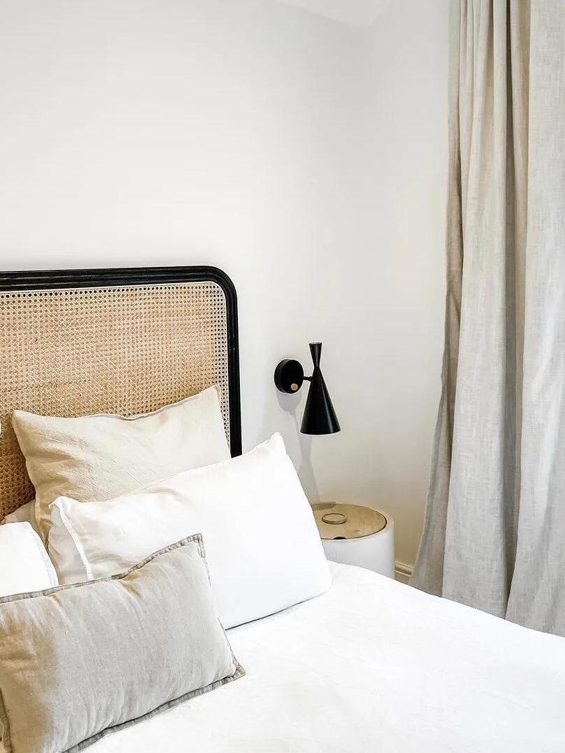 Black conical wall light above bedside table