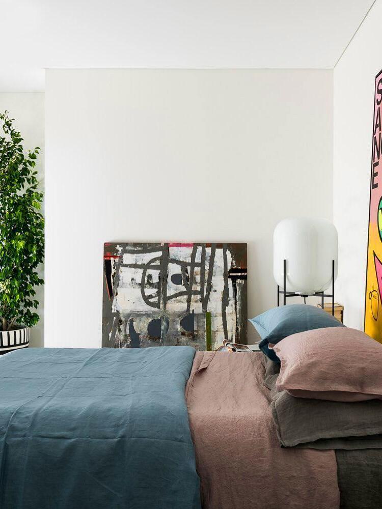 Pale glass floor lamp beside a bed in a bright bedroom.