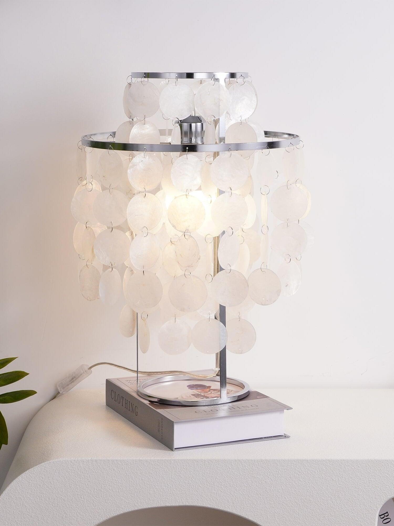 Warm-lit shell lamp on book with cord visible