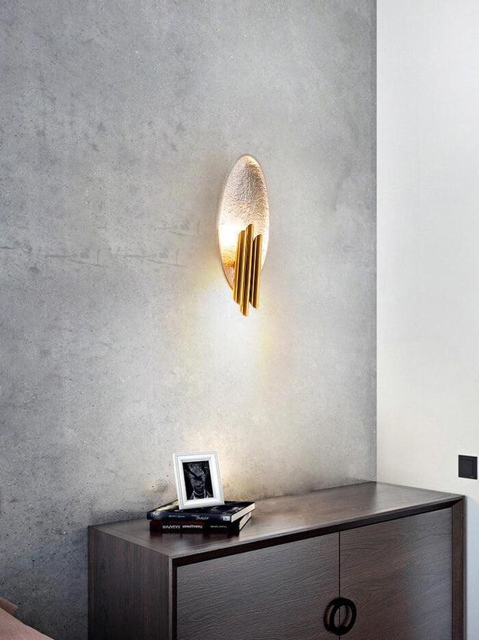 Silver-tone oval wall light above console on concrete-look wall