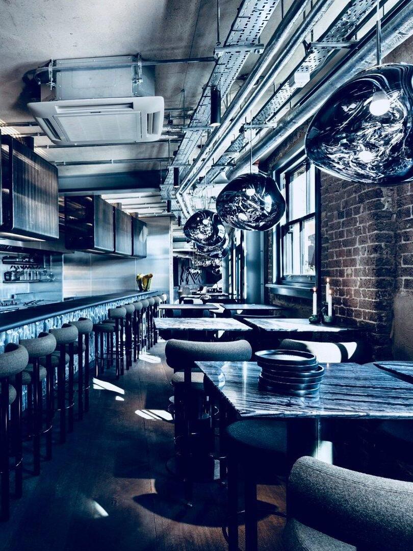 Dark metallic-looking pendants along a dining space