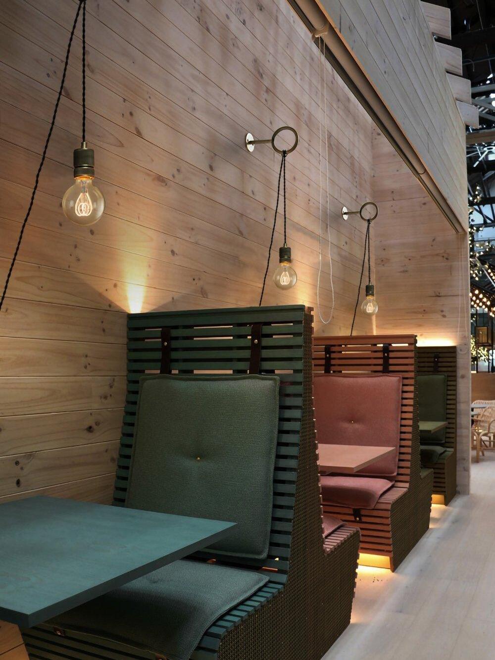 Multiple hanging loop lights across wood-panelled seating area
