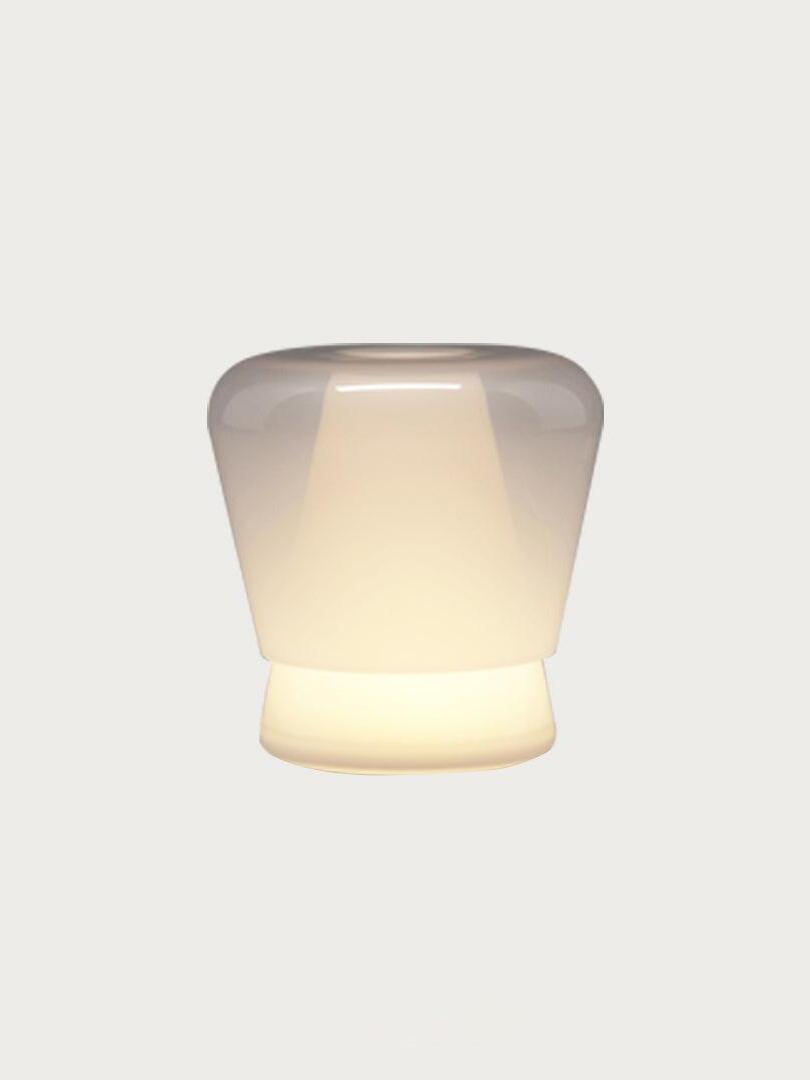 Lit white Jumelle table lamp on pale background