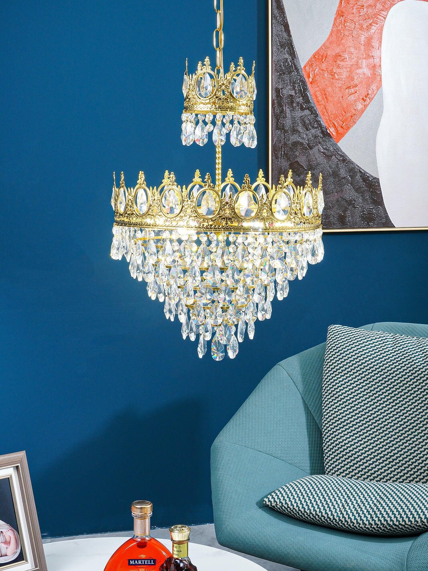 Crystal chandelier hanging beside a teal chair and abstract artwork against a deep blue wall