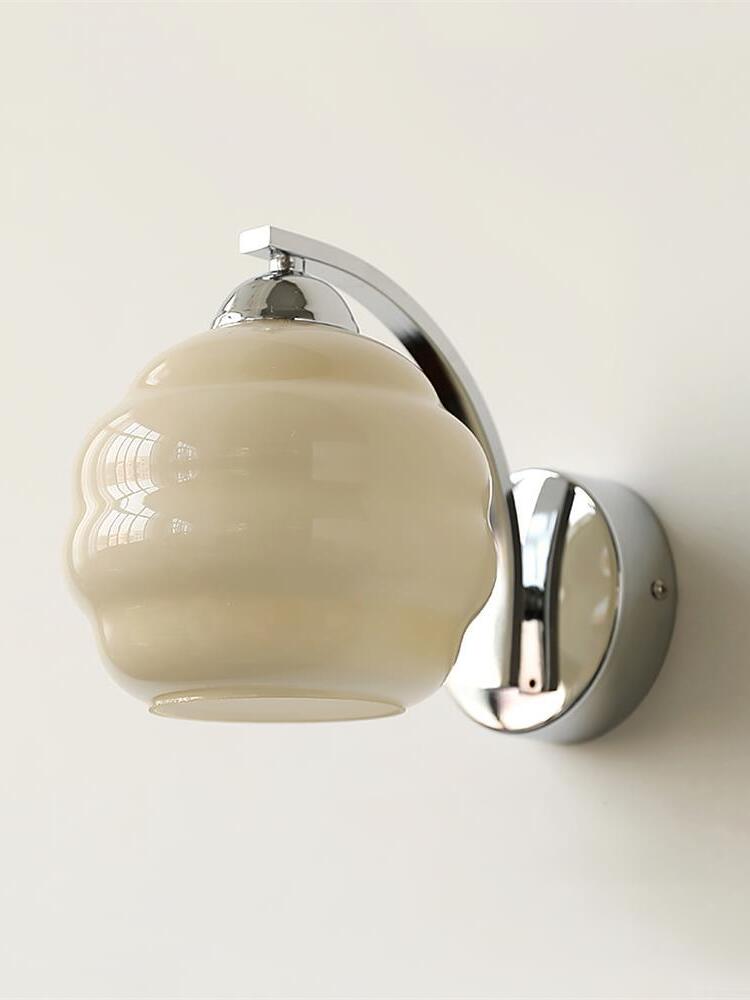 Beige contoured glass shade with open lower rim, chrome cap, curved arm and circular wall plate on the right