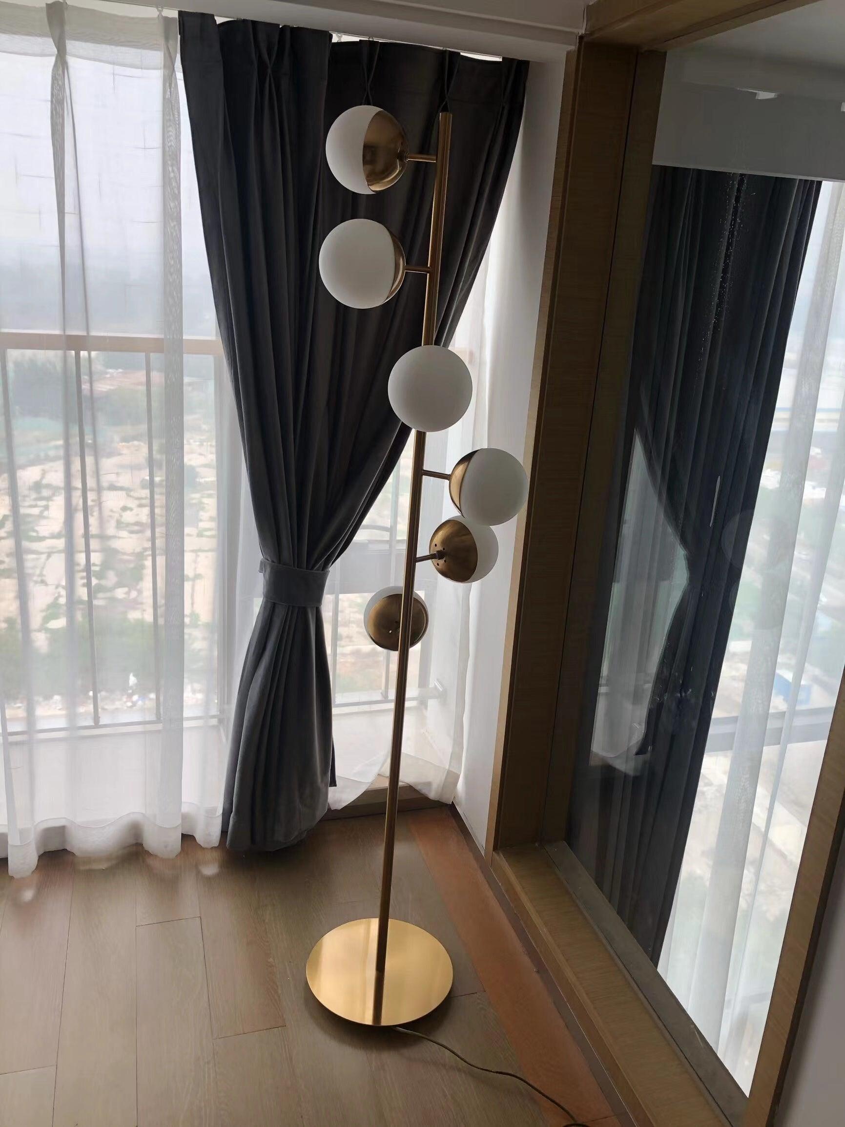 Tall globe lamp by glass door and curtains