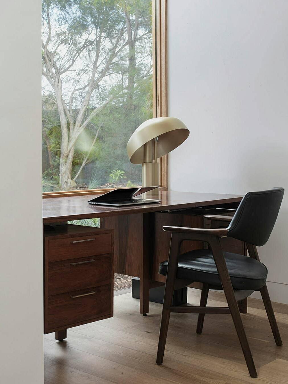 Gold table lamp on wood desk by window