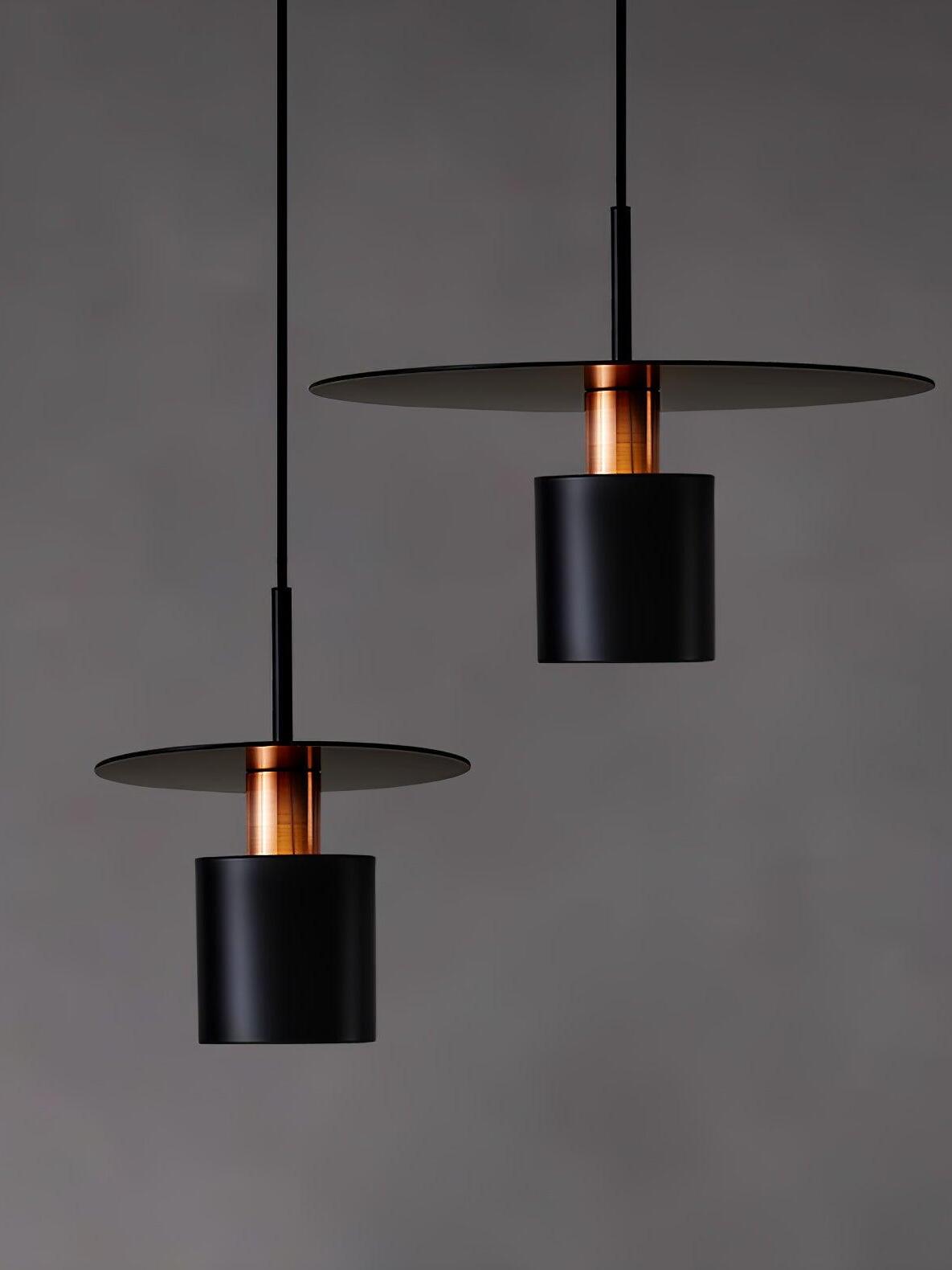 Two black disc pendants on dark wall