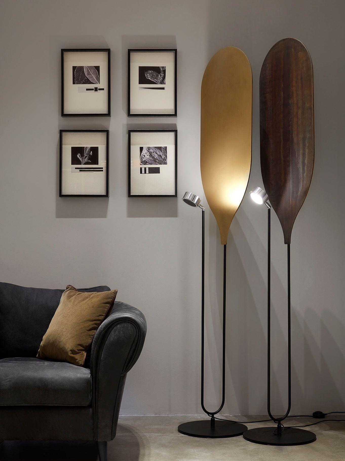 Golden and brown panel floor lamps beside armchair and framed artwork