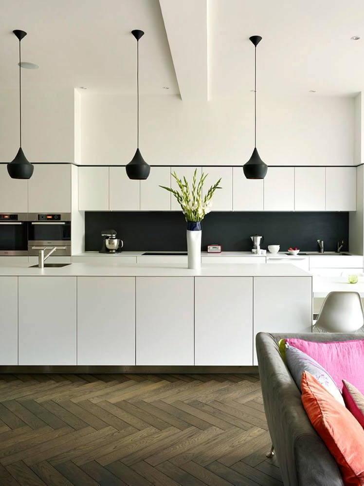 Black rounded pendants in front of white kitchen cabinets