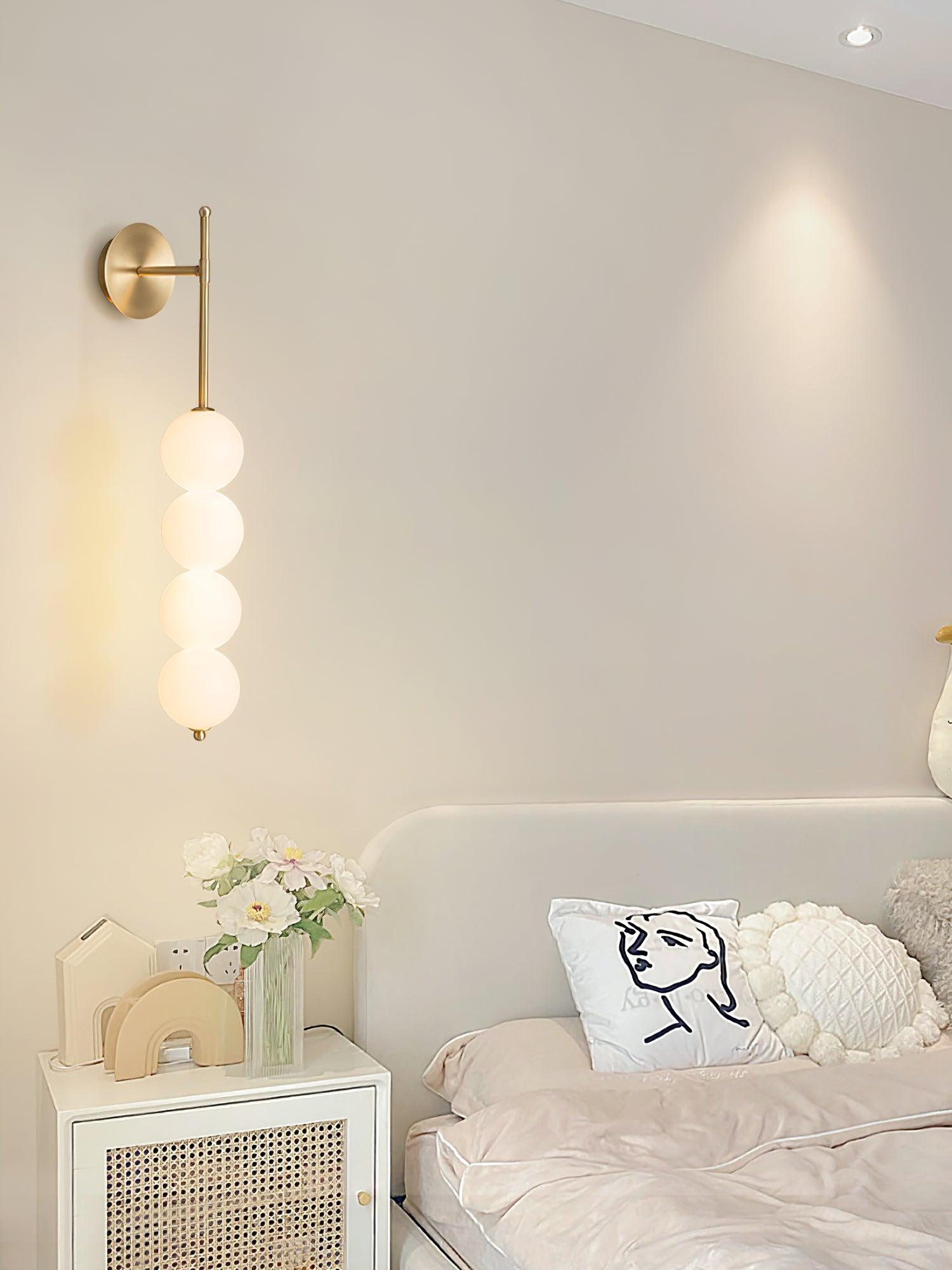 White globe wall lamp above a bedside cabinet