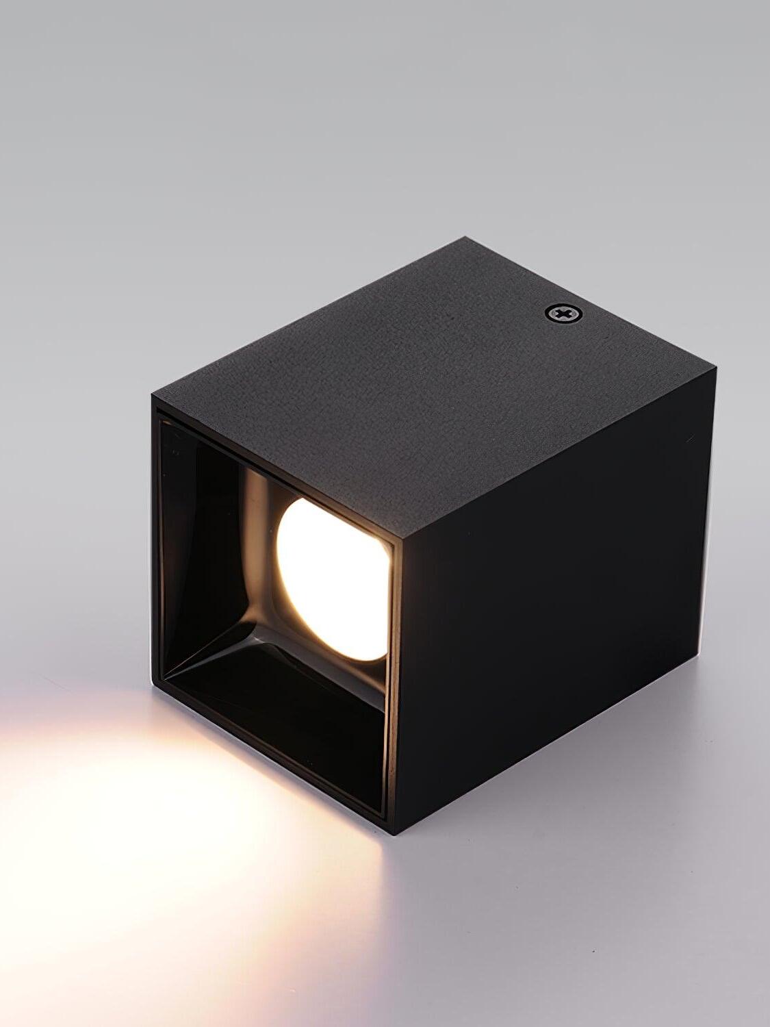 Black spotlight on its side casting a light pool, with a screw visible on the housing