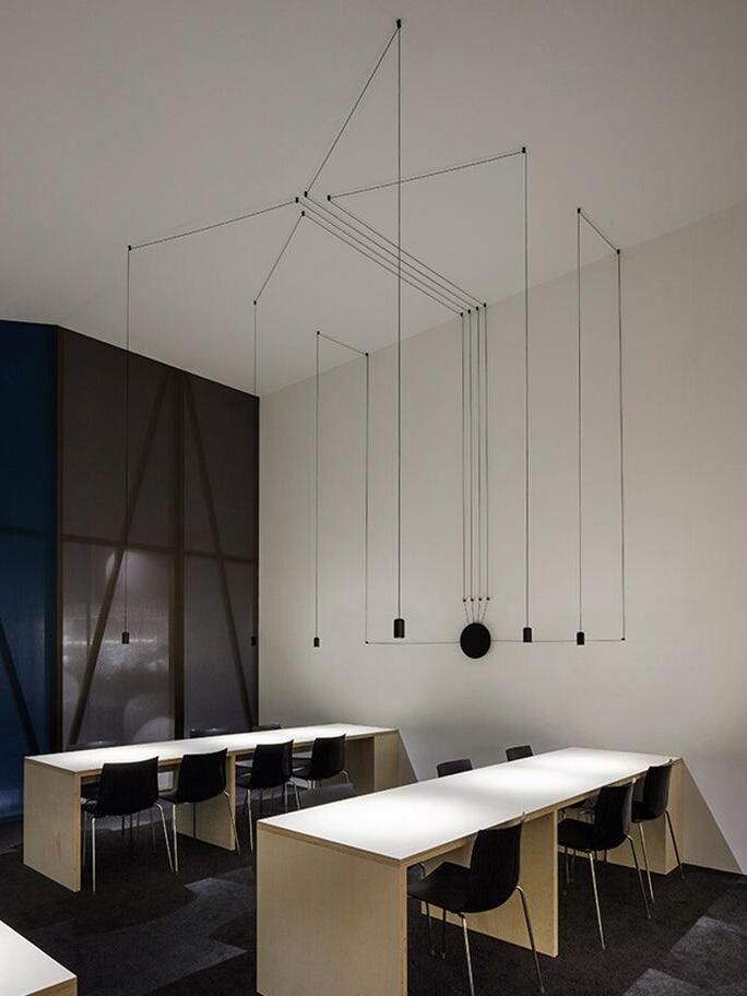 Geometric black cable routes above two white tables and dark chairs