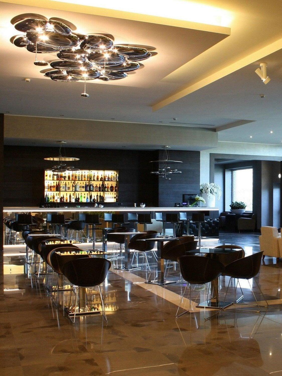 Reflective grouped ceiling forms above restaurant bar and dining furniture