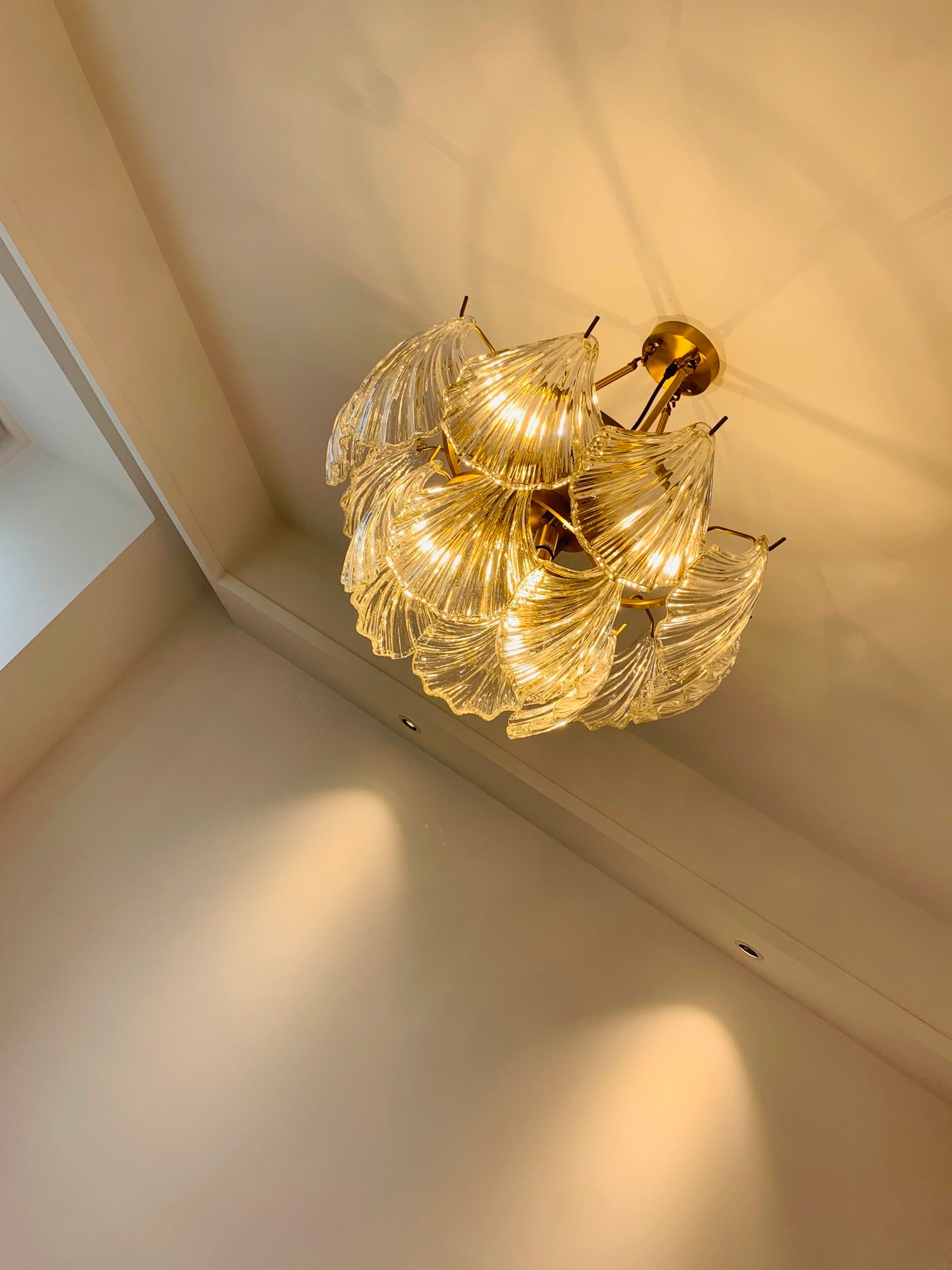 Illuminated ribbed glass fixture seen from below with patterns near a ceiling corner