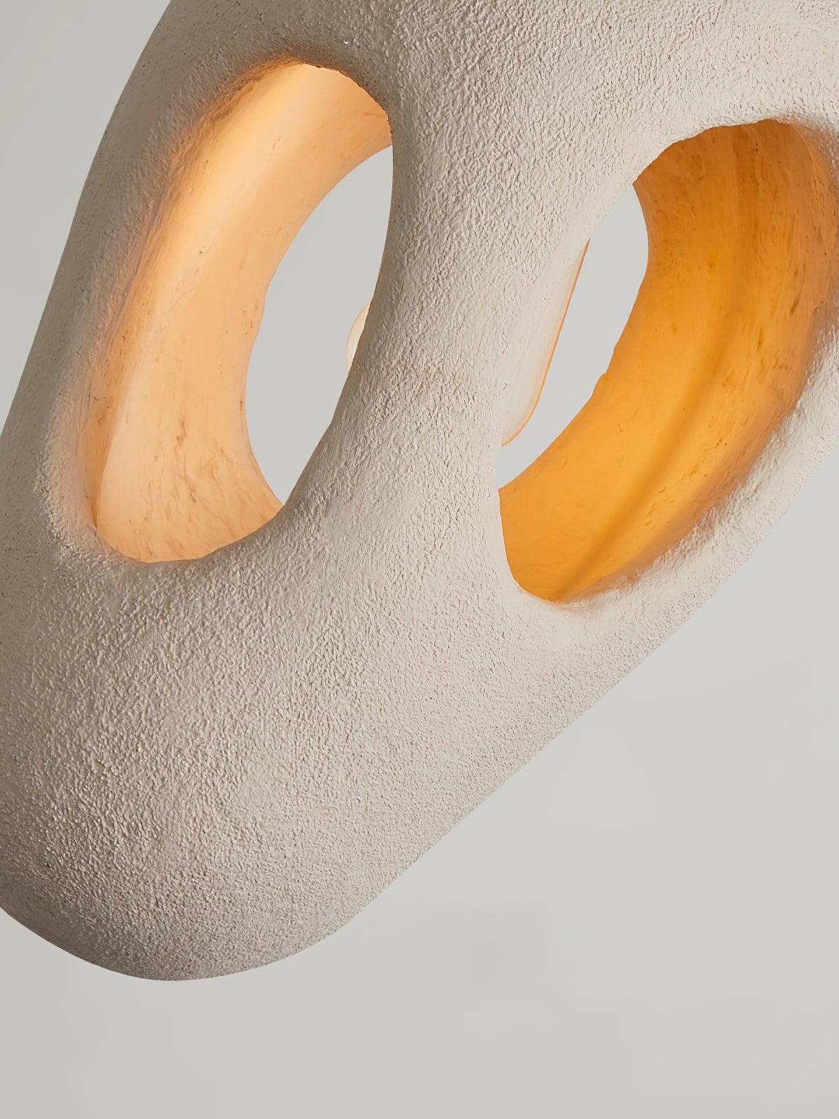 Angled close-up of a cream-looking textured body with warm illumination inside two irregular openings