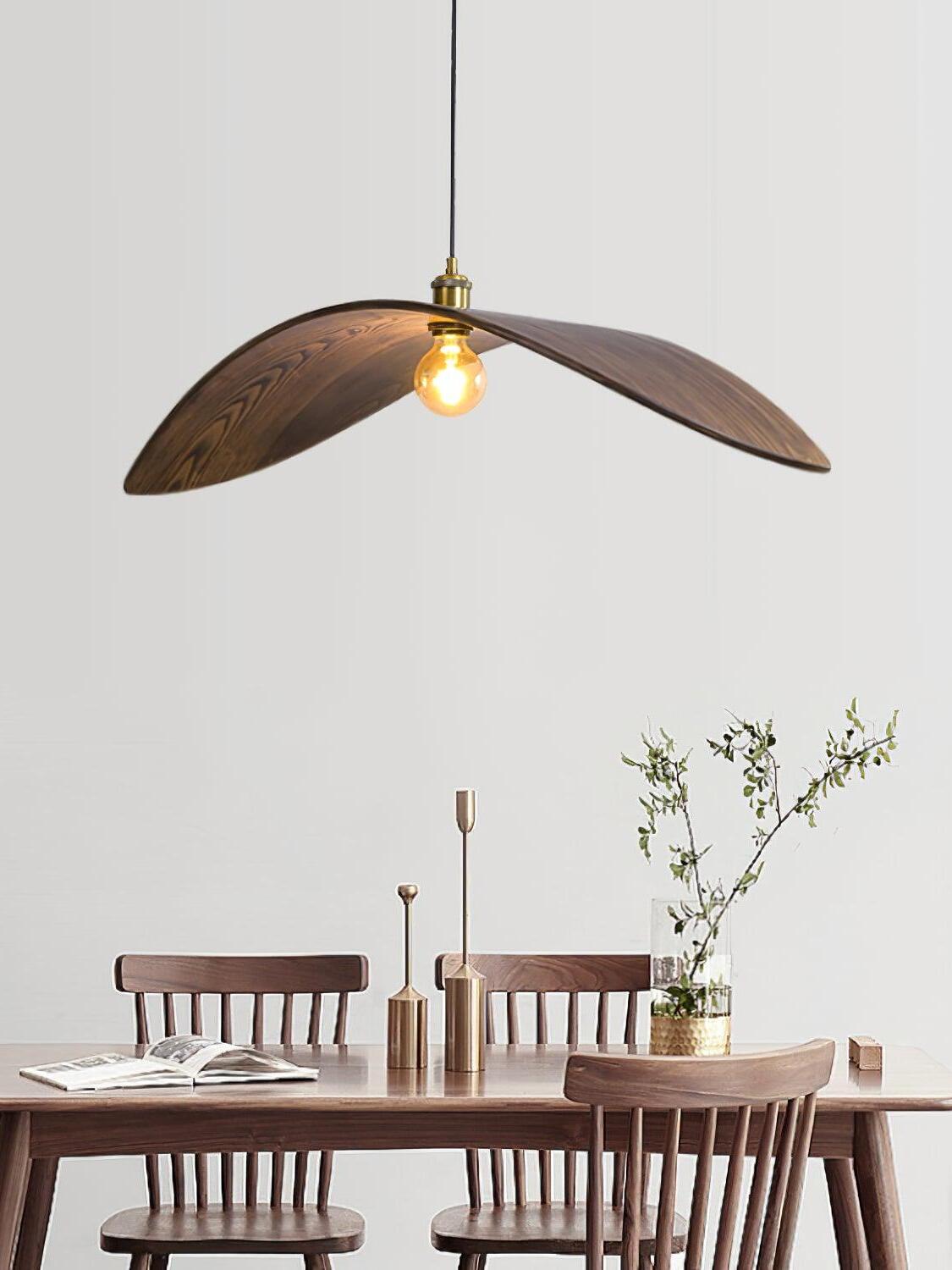 Curve pendant above a wooden dining table set with candlesticks and a vase of branches