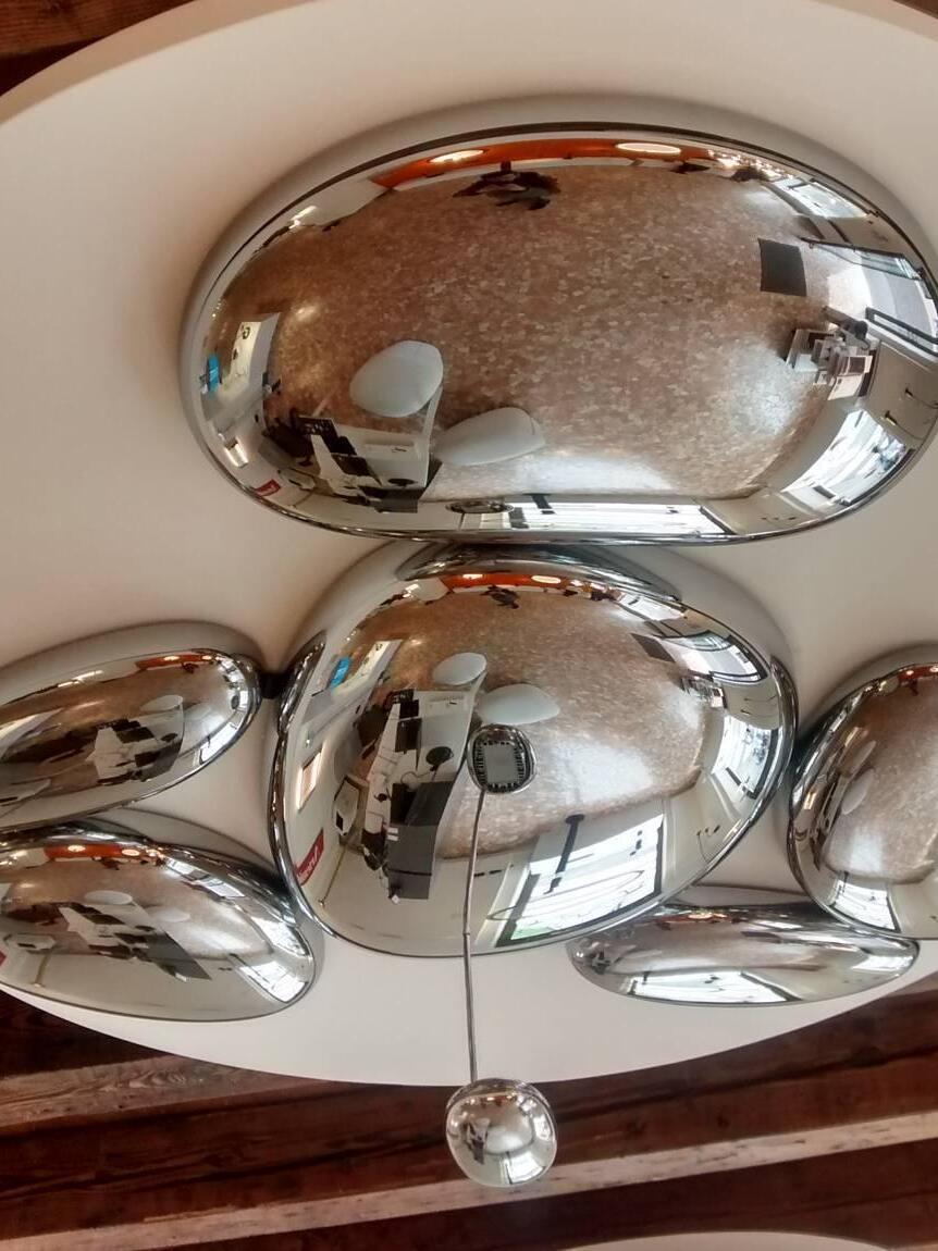 Reflective ceiling pebbles and small suspended oval below wood ceiling