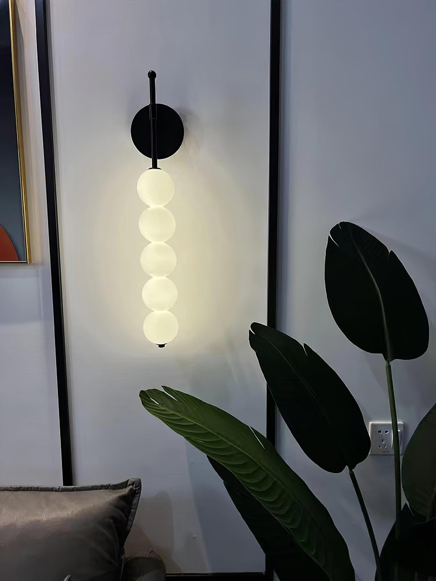 Illuminated Black globe wall lamp beside a plant