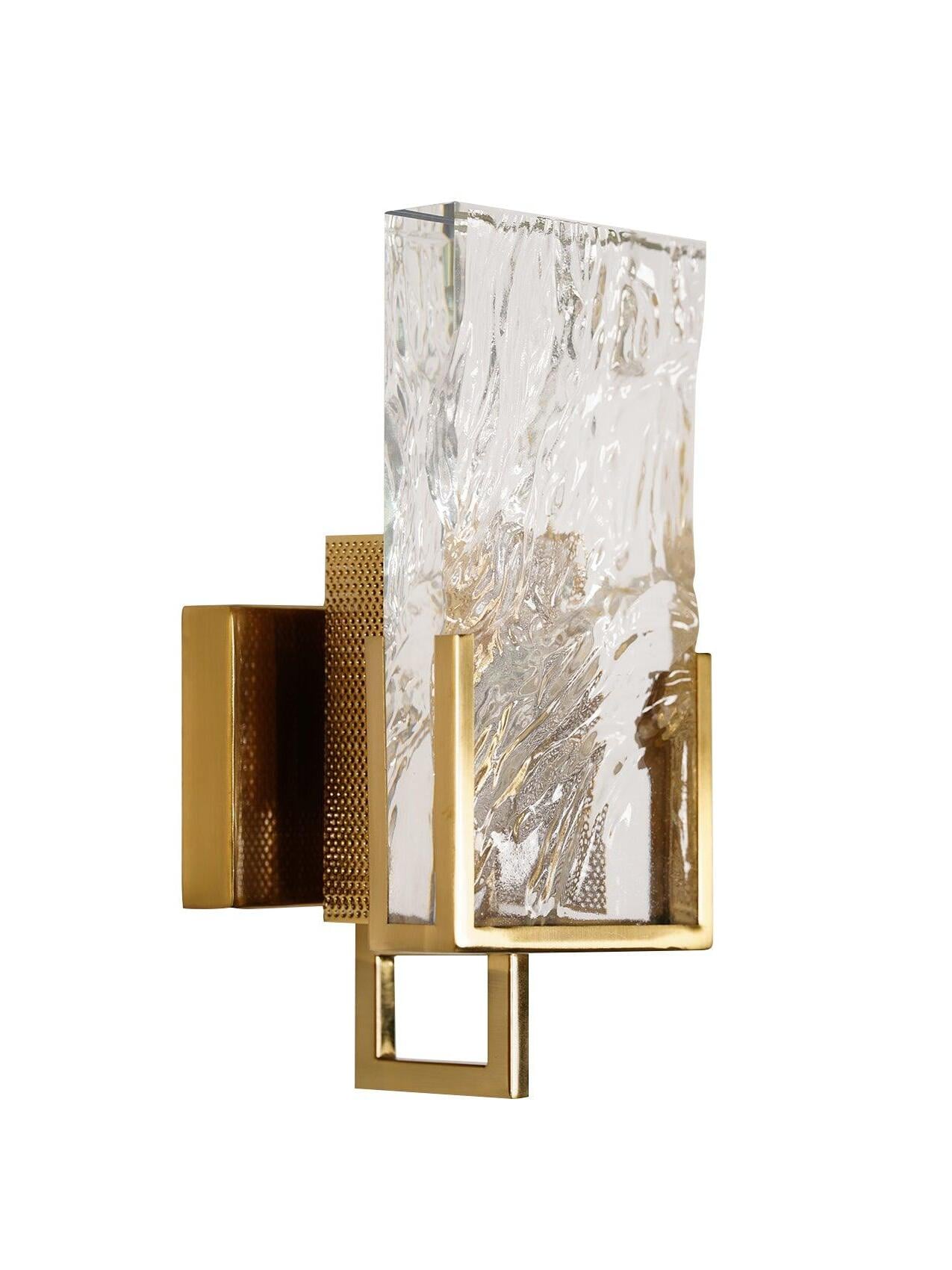 Ice Crystal wall light with a textured clear slab, brass-finish frame and square lower loop