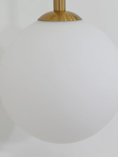 Close-up of a white globe shade with a gold-tone cap and slender rod above it