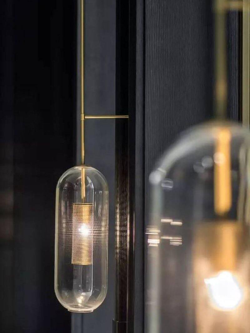 Glowing clear glass shade near a dark window with a second fixture blurred in the foreground