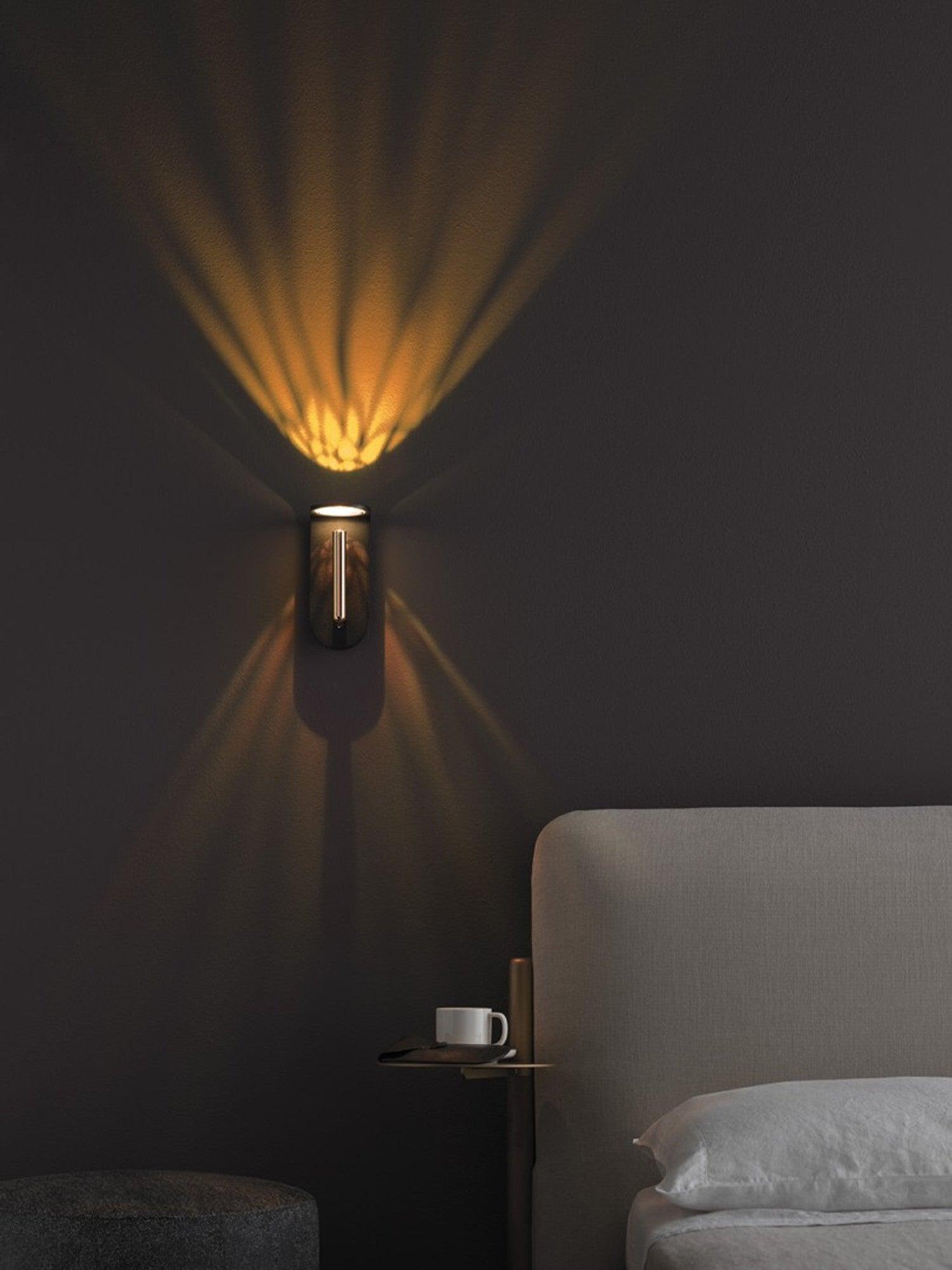 Black Nights wall light beside a bed, with fan-shaped light patterns on the dark wall