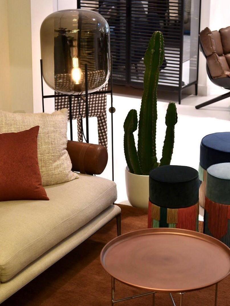 Smoke-tinted glass lamp near a white sofa and tall cactus.