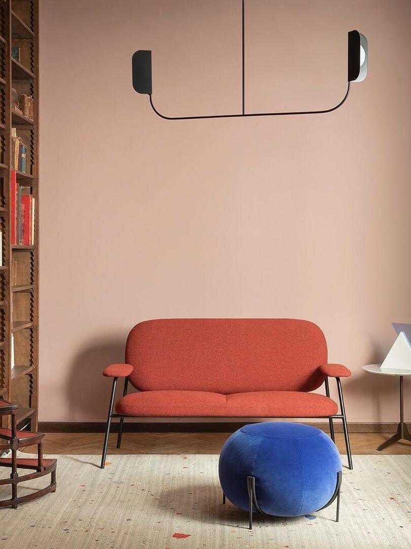 Wide black leaf-like fixture above a red sofa
