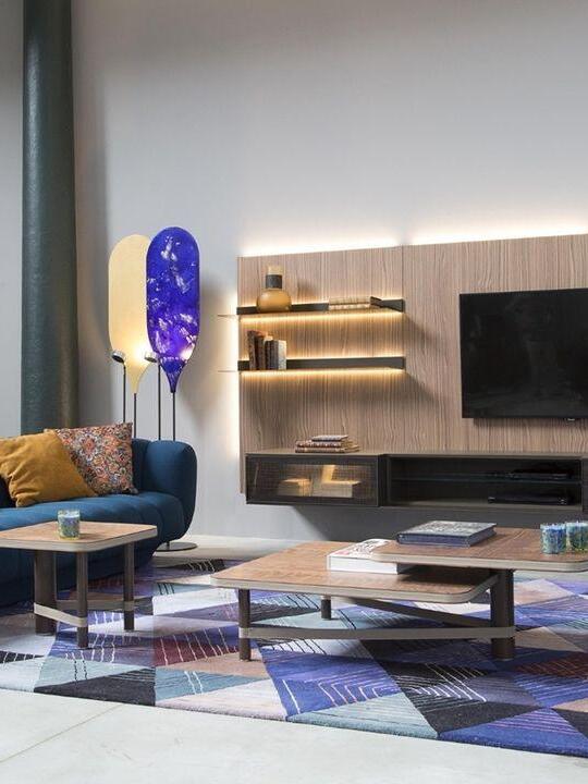 Blue and gold-toned panel lamps by curtains and seating near TV and shelving