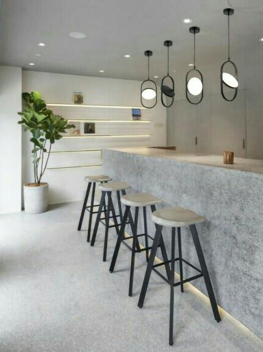 Four vertical oval-frame disc pendants on separate ceiling canopies above a gray bar counter and stools