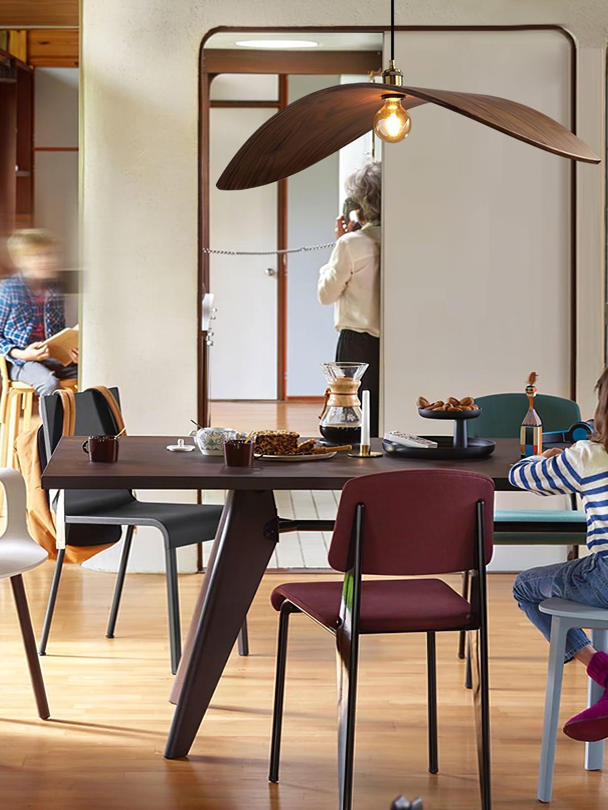 Curve pendant with an exposed bulb above a dark dining table and a red chair
