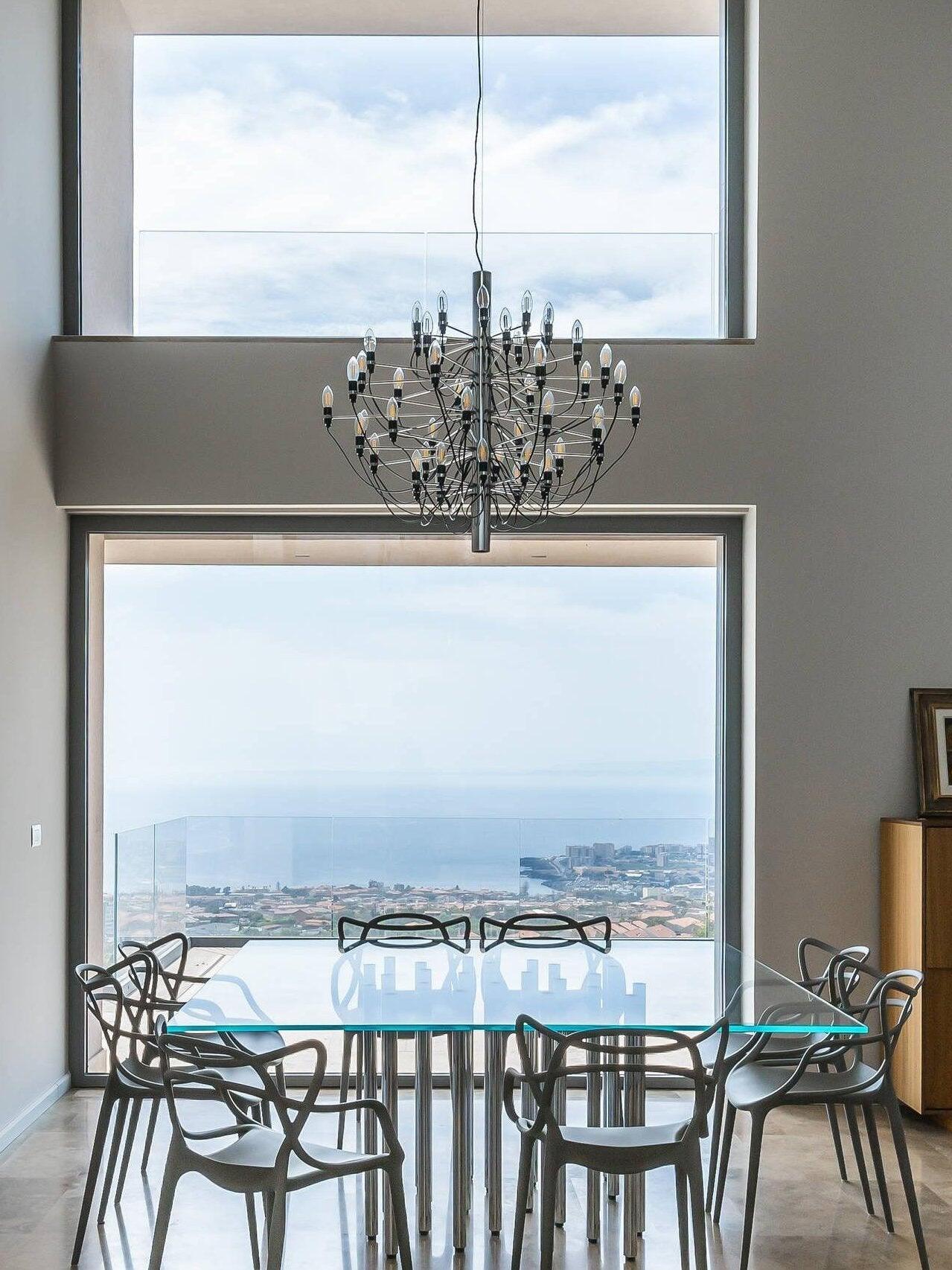 Dark chandelier above a glass dining table