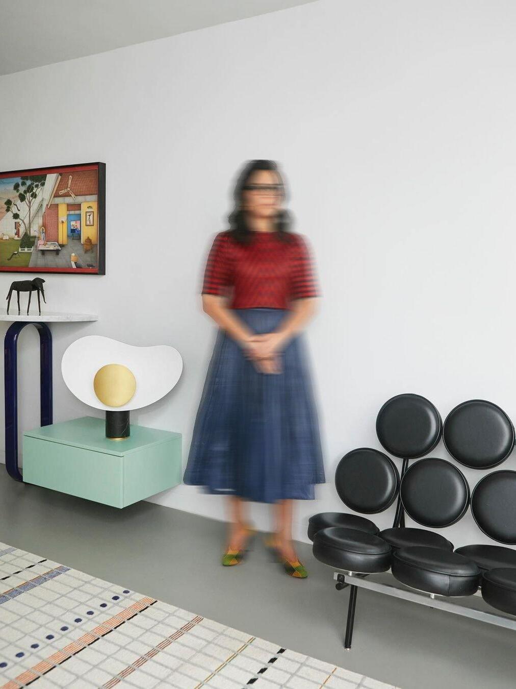 Person beside white and gold lamp on green cabinet