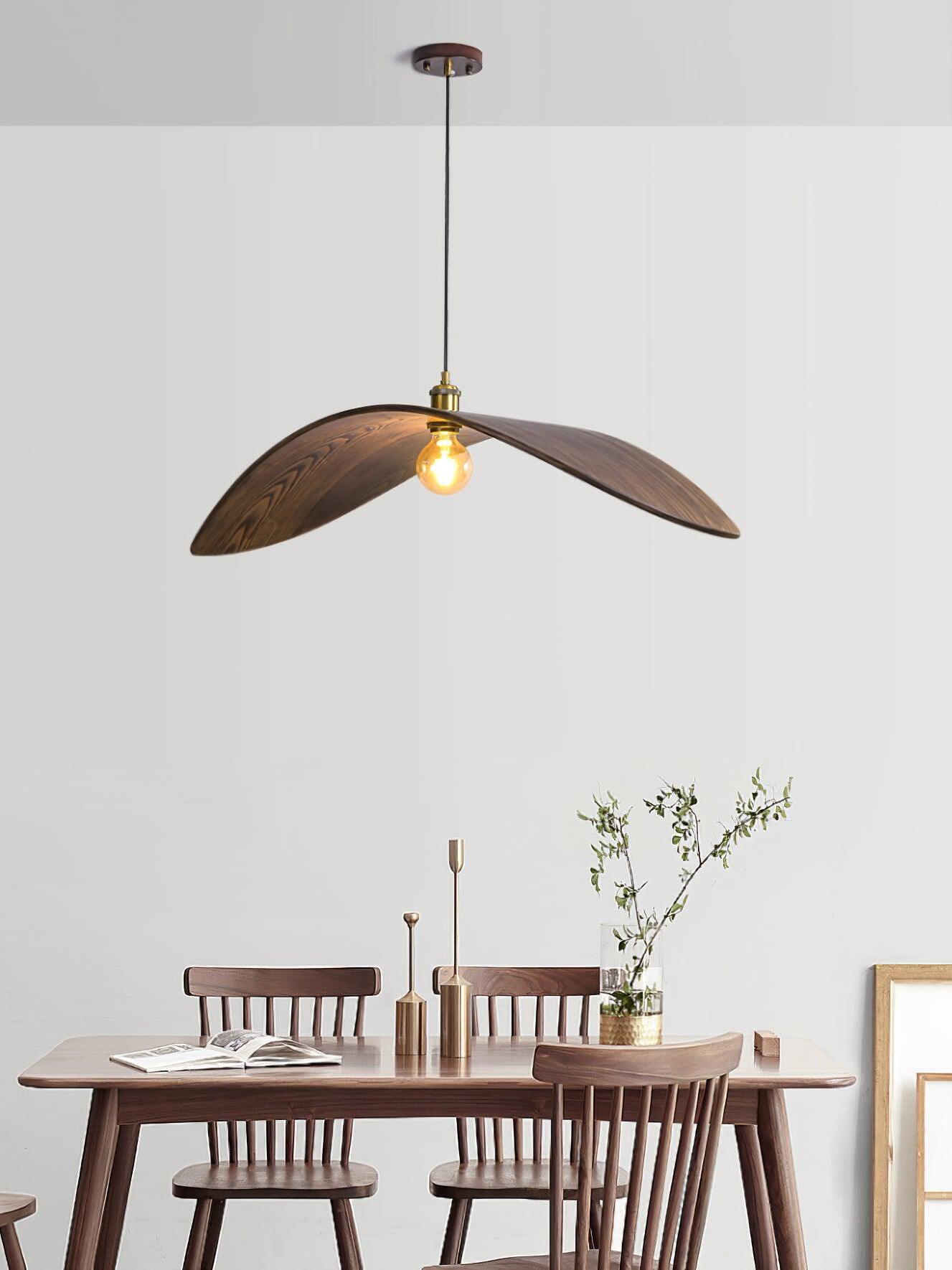 Full suspension view of the curved pendant over a wooden dining table and spindle-back chairs