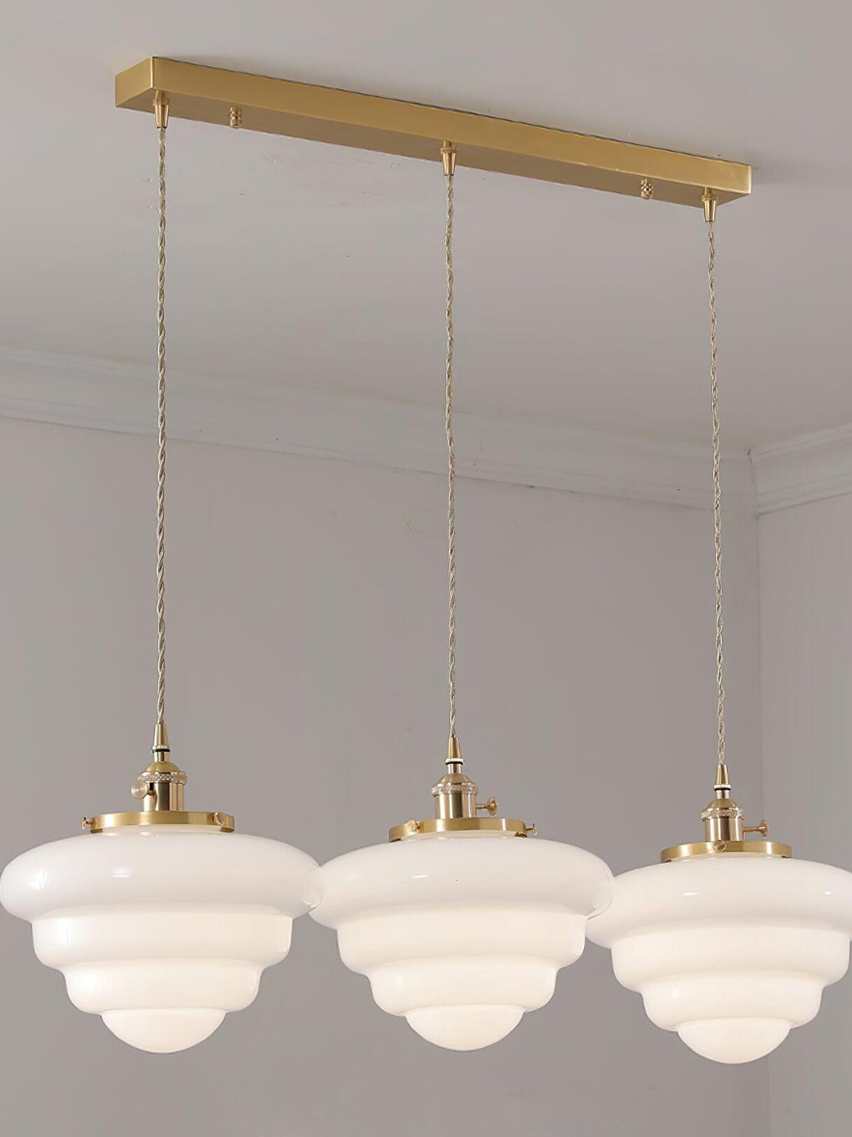 Atlas Model B three-head option with rounded white glass shades suspended beneath one long rectangular brass canopy
