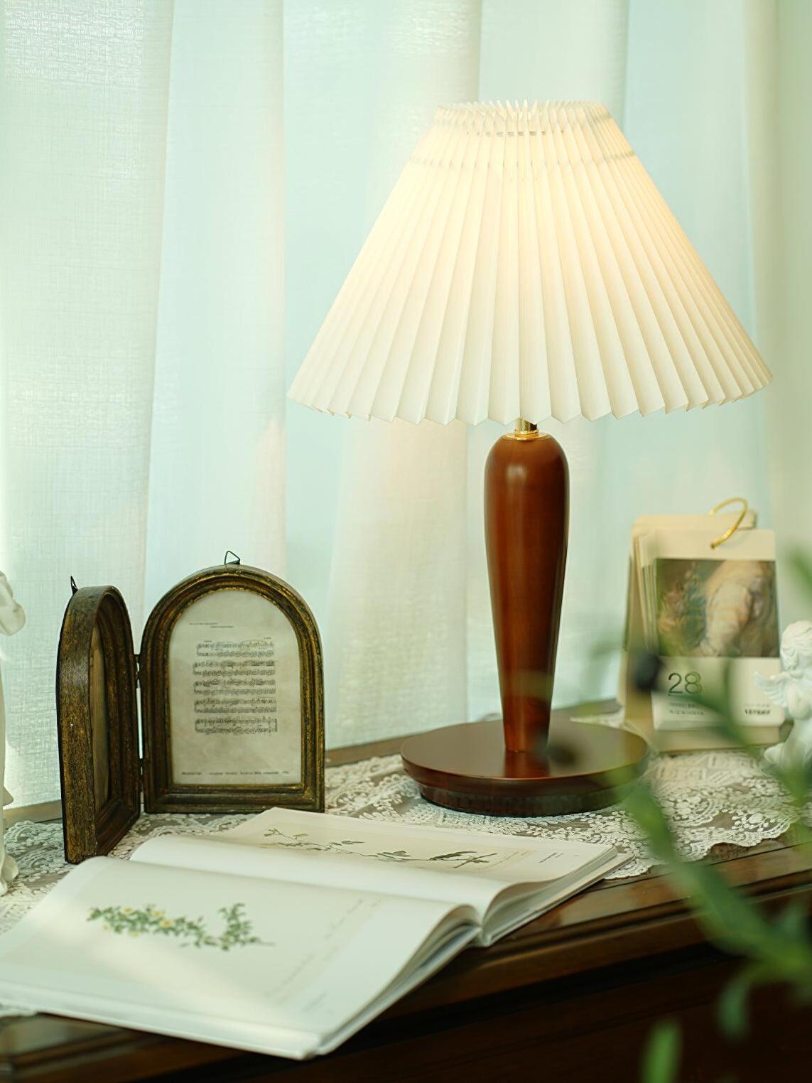 Brown pleated-shade lamp beside open book on dresser