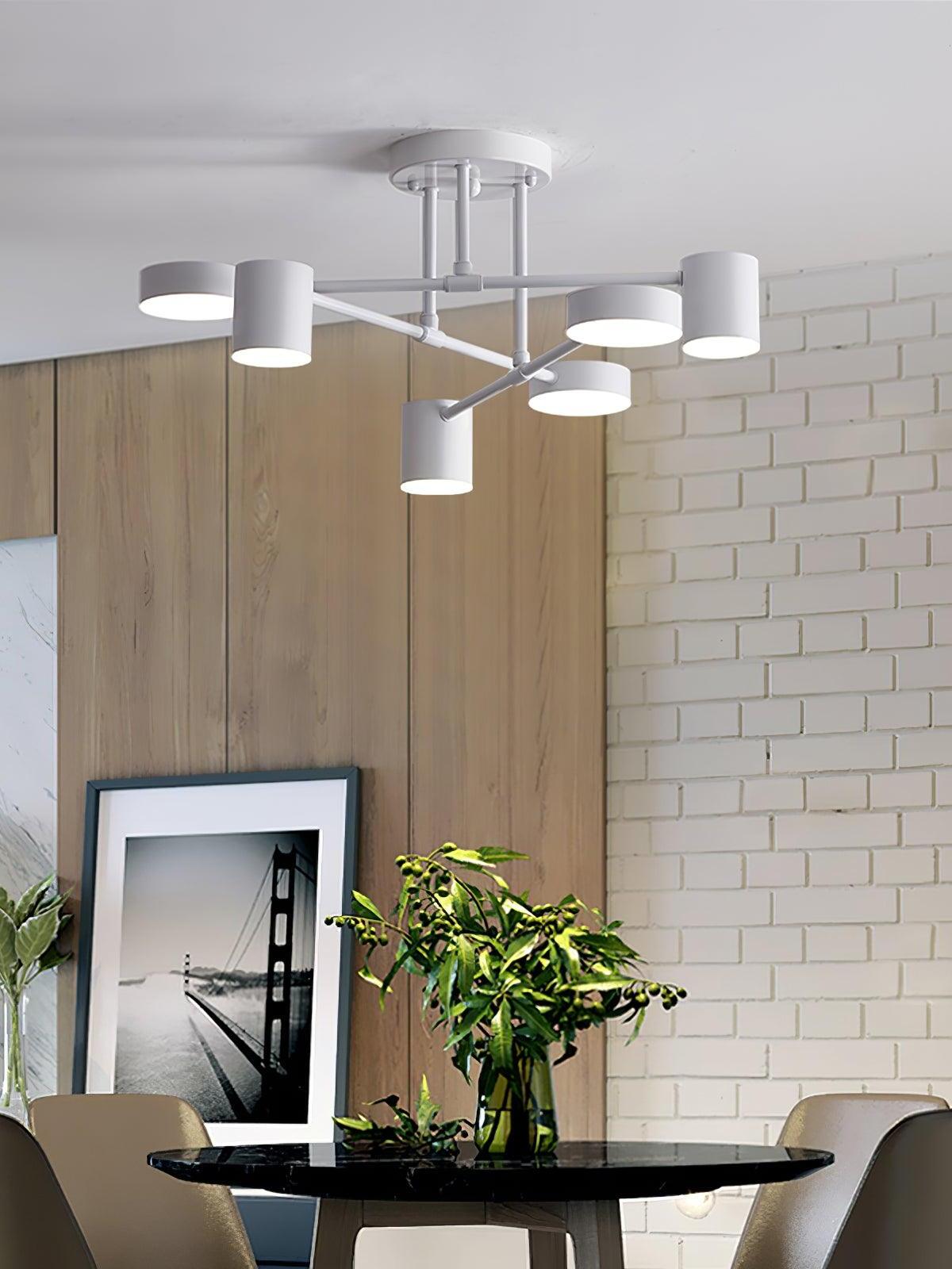 White six-head ceiling light above a round dark dining table, greenery, chairs, wood paneling and a white brick wall