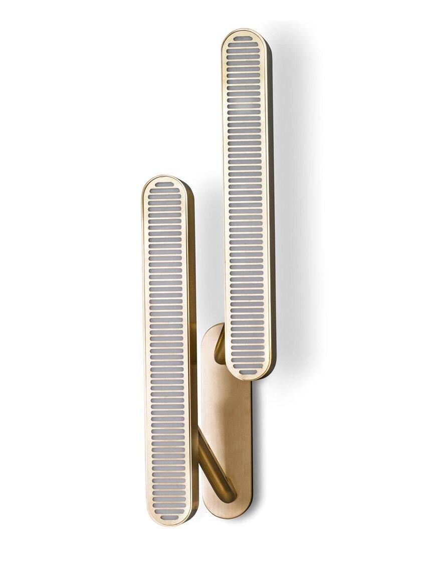 Close-up of two staggered rounded-end grille bars with pale slots and gold-tone arms on a common backplate against White