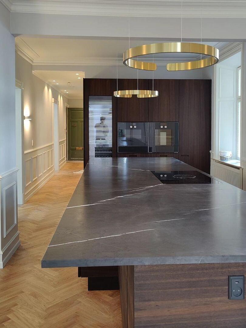 Gold-coloured ring pendant above a dark kitchen island