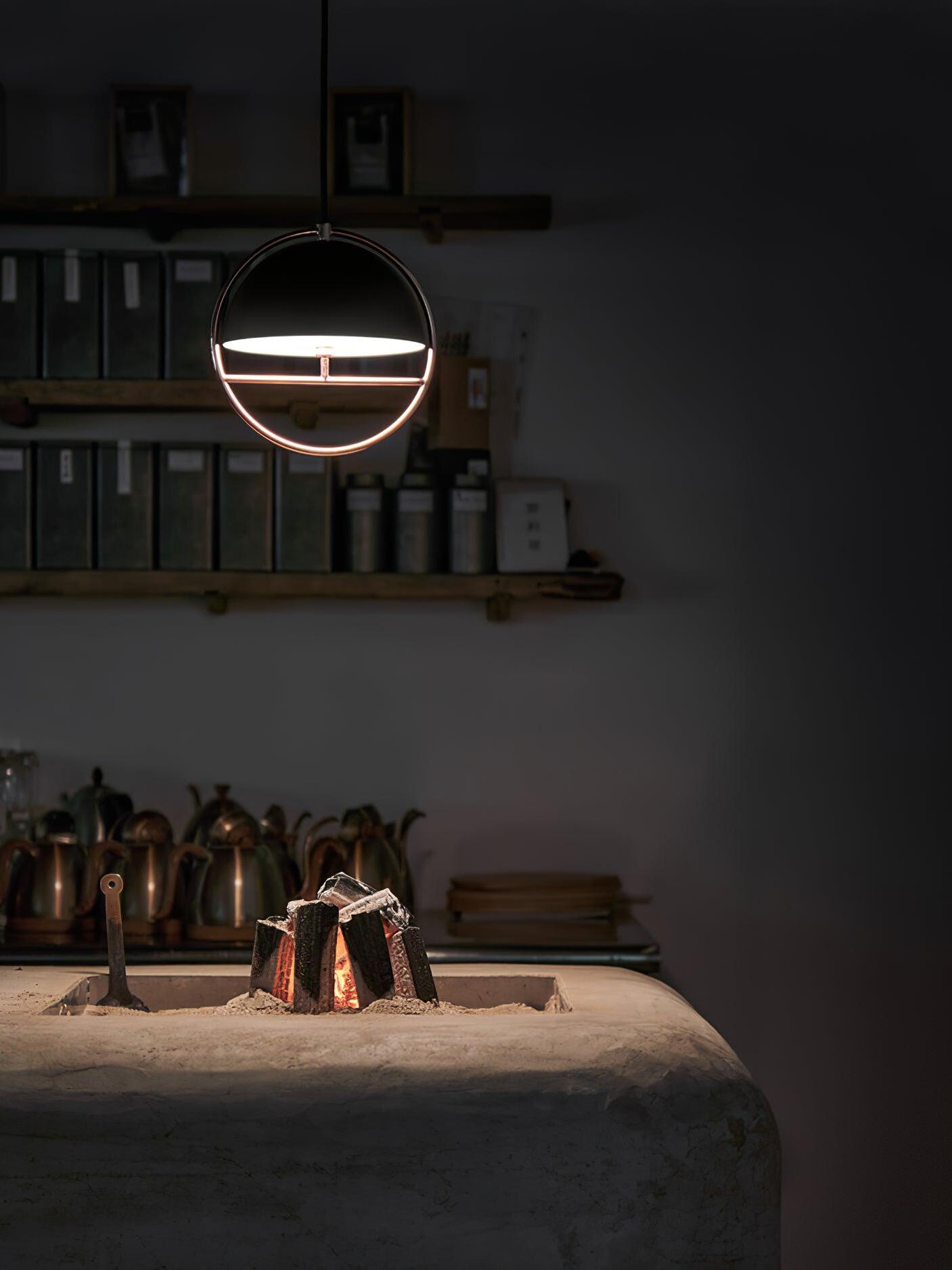 Lit black ring pendant above dark table