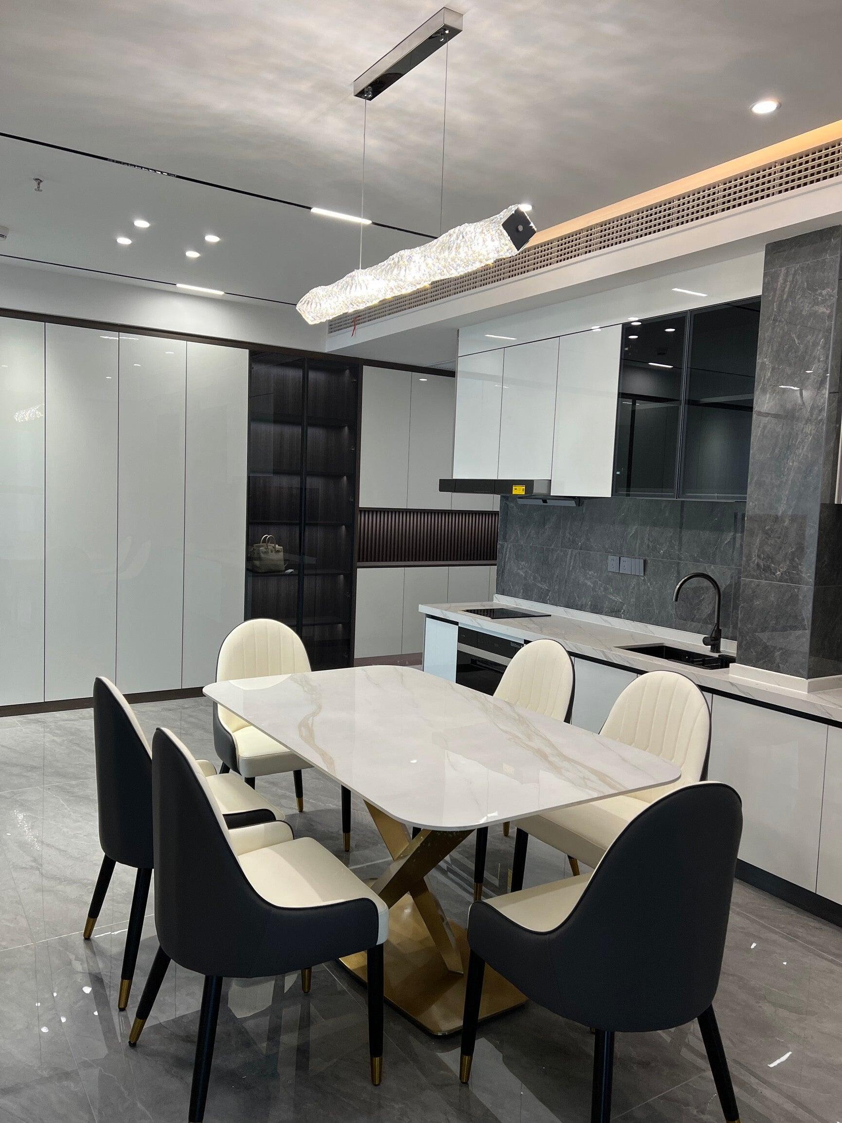 Alternate view of the long crystal pendant above a white table with contrasting black and white chairs