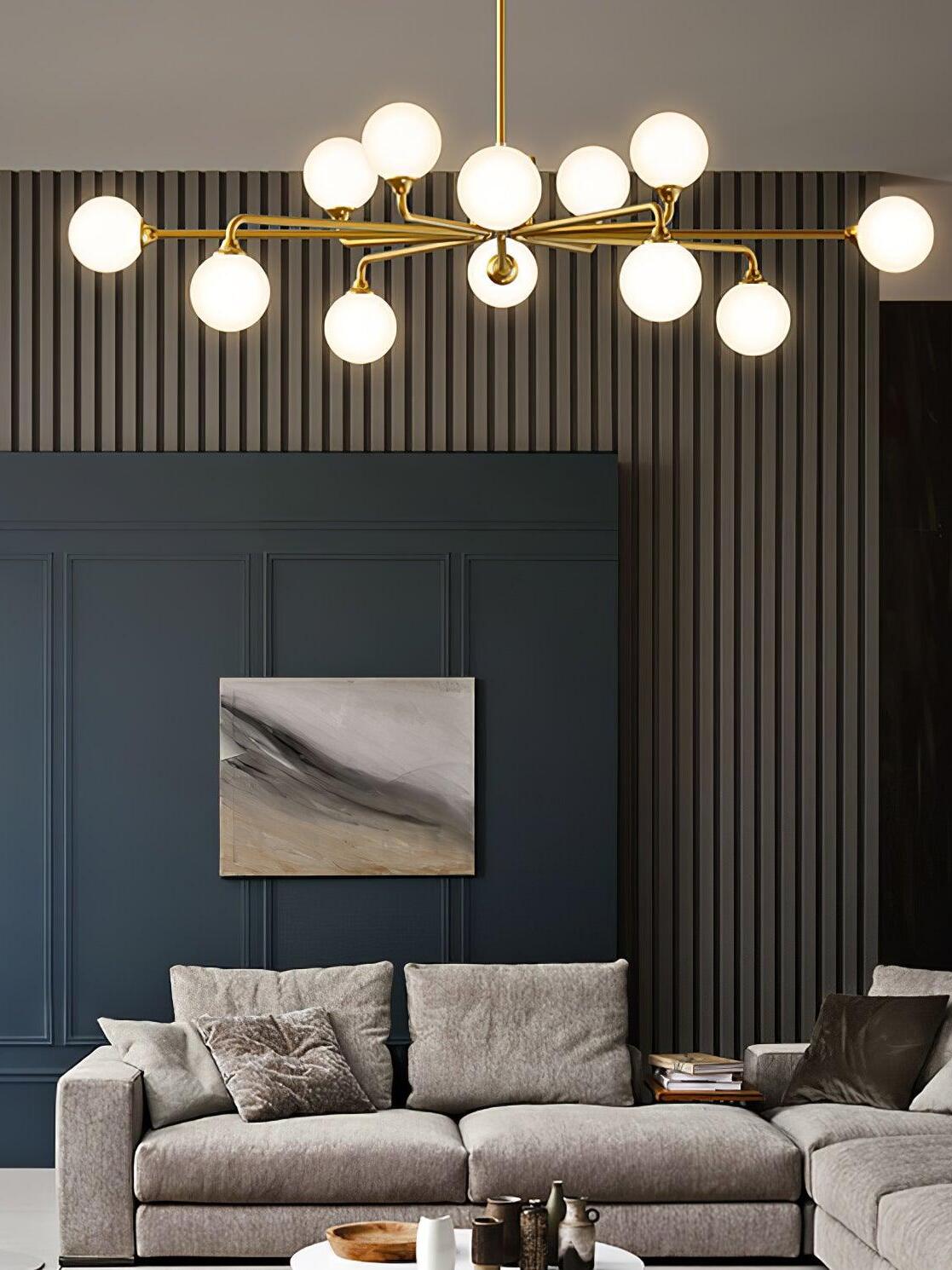 Wide brass globe chandelier above grey sofa