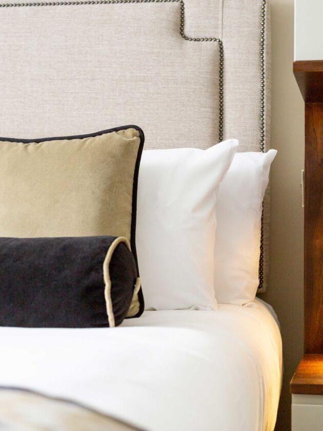 Small recessed reading light beside upholstered bedding